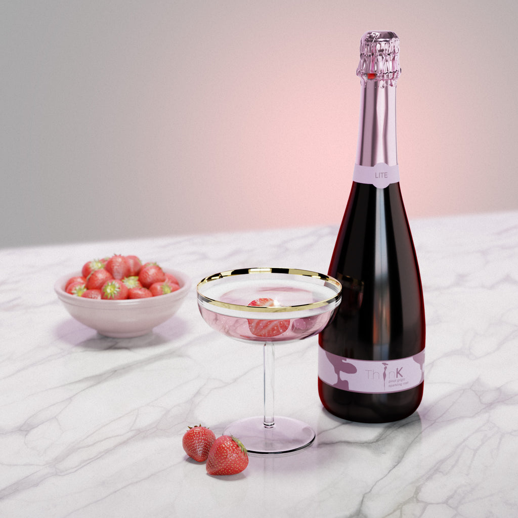 A bottle of Organic Vegan Sparkling Rosé resting on a marble table alongside a glass of wine
