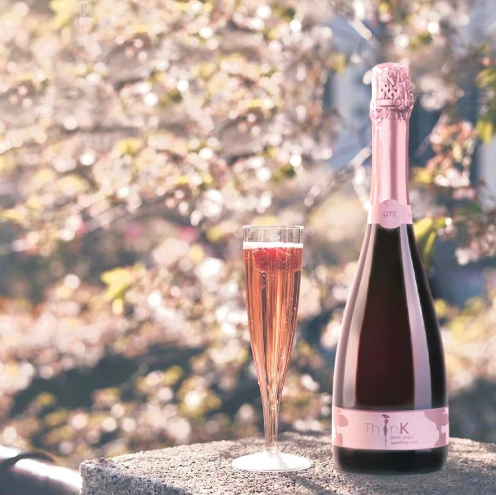 A bottle of ThinK Wine 75 cl Organic Vegan Sparkling Rosé resting next to a freshly poured glass of wine