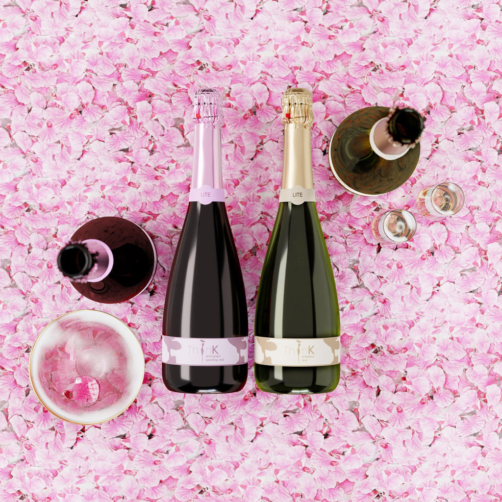 Two bottles of 75 calories Organic Vegan Sparkling Wine resting on a bed of flower pettles
